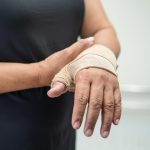 asian middleaged lady woman use elastic bandage treating de quervain syndrome hand finger office.jpg