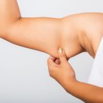 close up asian woman pulling excess fat her arm.jpg